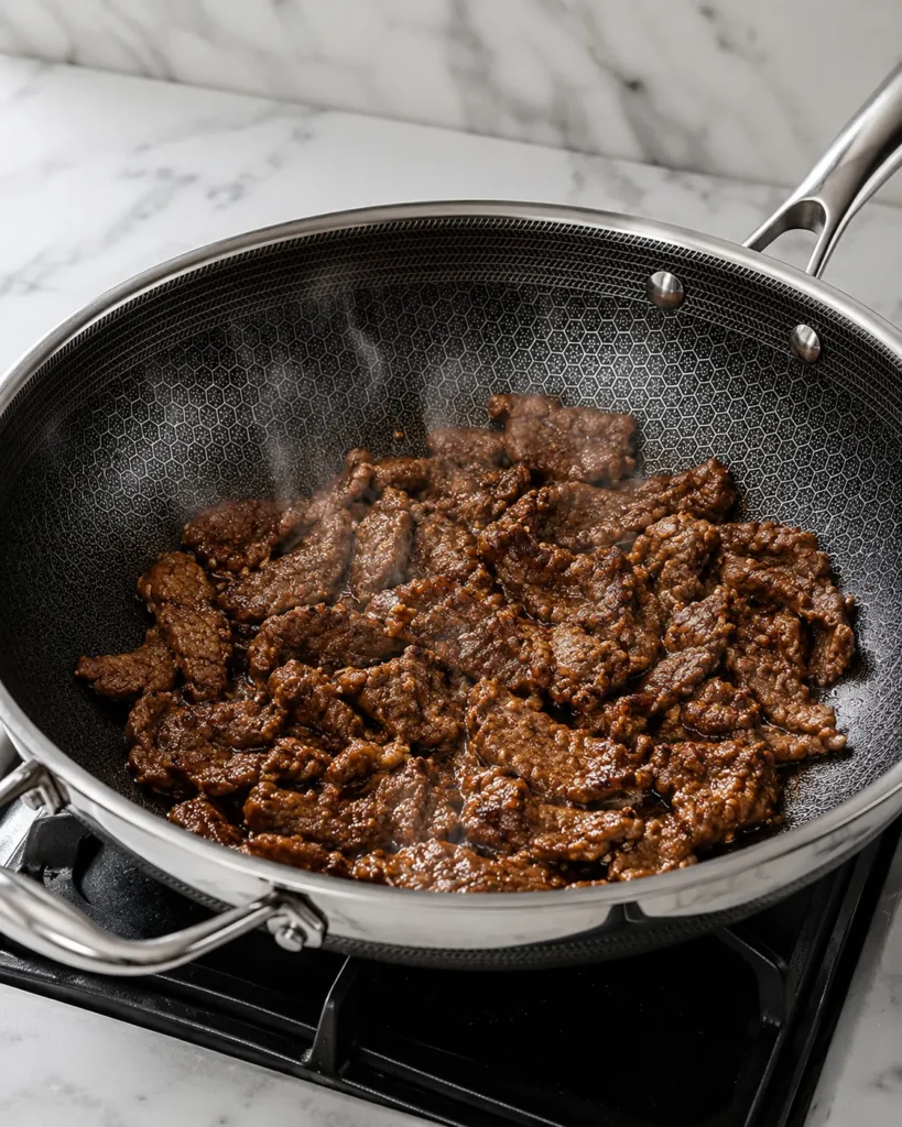 Caramelized Korean beef cooking in skillet with glossy marinade for beef bibimbap recipe