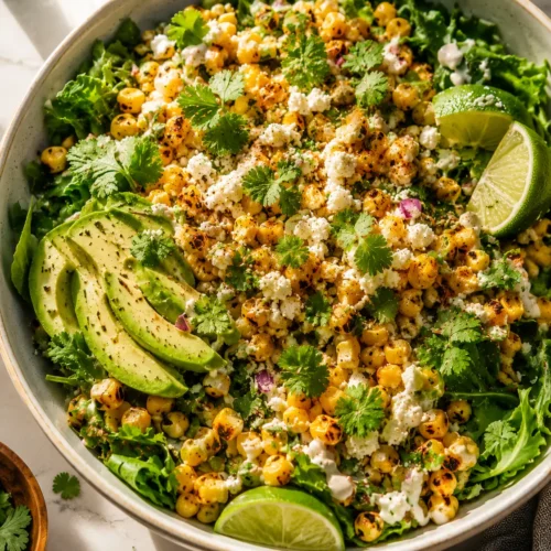 Easy esquites recipe with greens, cotija cheese, and avocado on a plate